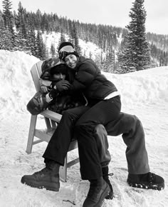 two people sitting on a bench in the snow