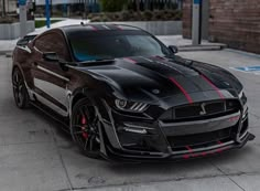 a black sports car with red stripes parked on the street