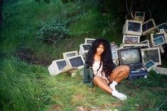 a woman sitting on the ground in front of old televisions