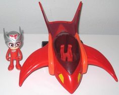 a toy figure next to an action figure on a white surface with a wall in the background