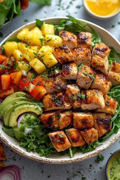 a bowl filled with chicken, avocado and pineapple salad on top of a table