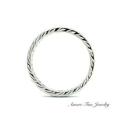 a white gold wedding ring with braiding on the sides and an inscription underneath it