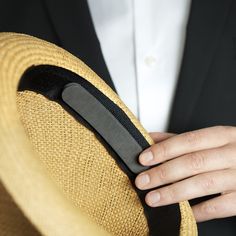 a person in a suit and tie holding onto a straw hat with a black band