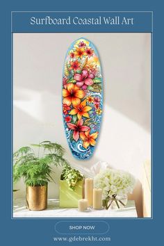 a surfboard with flowers painted on it next to some candles and potted plants