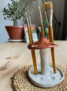 there are four brushes in the holder on the table and one is holding two paintbrushes