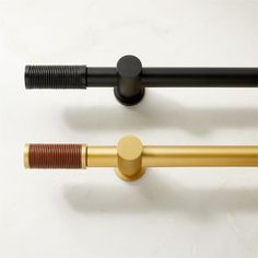 three different types of metal rods on a white surface, one black and one gold