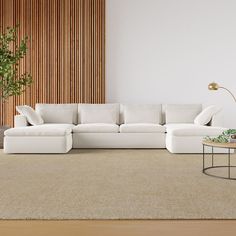 a large white couch sitting in a living room next to a coffee table and potted plant