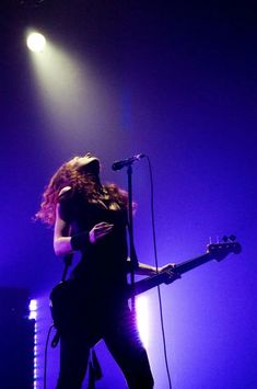 a woman with long hair playing guitar on stage