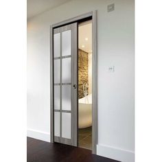 an open door leading to a bathroom with a bathtub in the background and wood flooring