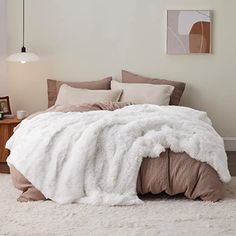 a bedroom with a bed covered in a white fluffy blanket