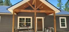 a gray house with a wooden roof and white trim on the front door is surrounded by construction materials