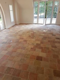 an empty living room with french doors and brick floor