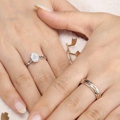 two women's hands with wedding rings on top of each other and leaves in the background