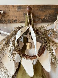 a wreath is hanging on the wall with two bells and some fabric pieces around it