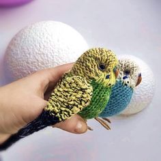 two small birds sitting on top of each other's fingers next to white balls