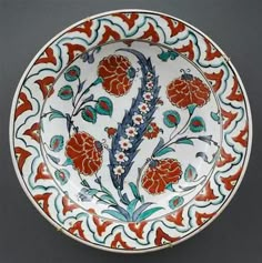 a decorative bowl with red flowers and leaves on it's rim is displayed against a gray background