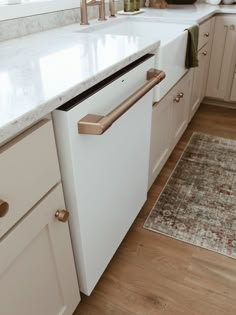 a white dishwasher sitting on top of a kitchen counter next to a rug