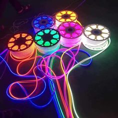 several different types of neon lights on a black surface with wires and cords attached to them