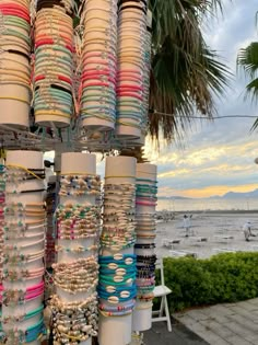 many bracelets and necklaces are on display near the beach in front of palm trees