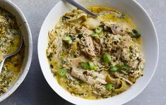 two white bowls filled with food on top of a gray table next to each other