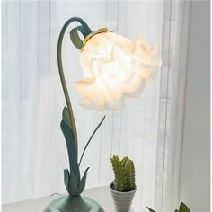 a white flower sitting on top of a table next to a green potted plant