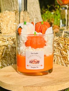 an orange drink in a glass with whipped cream and pumpkins around it on a wooden table