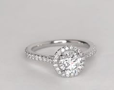 a white gold engagement ring with diamonds on the band and an oval halo setting in the center