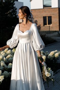 a woman in a white dress is walking down the street