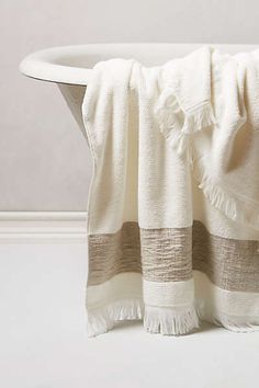 a white bath tub sitting next to a towel on top of a wooden table in front of a wall