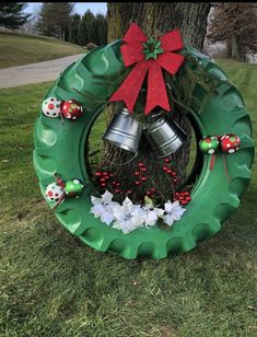 a green wreath with bells and flowers on the grass in front of a large tree