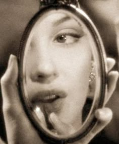 a woman looking through a magnifying glass to see her face in the mirror