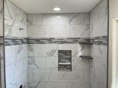 a walk in shower sitting next to a toilet and tiled walls with shelves on each side