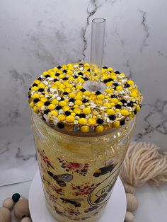 a glass jar with yellow and black beads on it