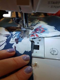 a woman's hand is using a sewing machine to sew on the fabric