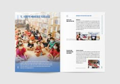 an open book with children sitting on the floor in front of bookshelves and people standing around