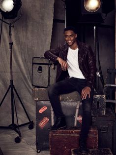 a young man sitting on top of luggage in front of a camera and lighting equipment