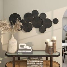 a living room with a table, vase and clock on the wall next to it