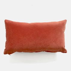 an orange pillow sitting on top of a white table