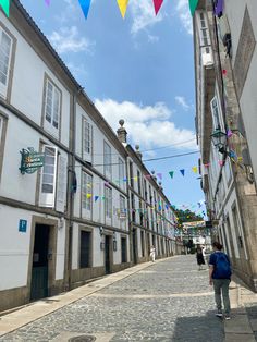 people are walking down the street in front of buildings with colorful flags hanging above them