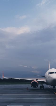 an airplane is parked on the tarmac at dusk or dawn with clouds in the background