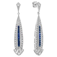 A fabulous pair of Art Deco inspired blue sapphire and diamond earrings. These wonderful earrings have a long French cut blue sapphire and diamond set arrow shape drop suspended from a milgrain set round diamond top. They are beautifully elegant when worn as they have wonderful movement. Earrings Information Style: Art Deco Metal: 18K White Gold Width: 10 mm. Length: 51 mm. Weight: 8.90 g. (approx. in total) Backing: Push Back Gemstones I Type: Diamond Shape: Round Average Color: H Average Clari Art Deco Blue Jewelry With Single Cut Diamonds, Blue Art Deco Jewelry With Single Cut Diamonds, Luxury Platinum Blue Earrings, Luxury Blue Platinum Earrings, Art Deco White Gold Diamond Earrings, Art Deco Diamond Earrings For Formal Occasions, Luxury Sapphire Diamond Earrings With Brilliant Cut, Formal Sapphire Diamond Earrings With Diamond Accents, Formal Sapphire Dangle Diamond Earrings