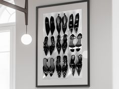 black and white photograph of pairs of shoes hanging on the wall in front of a window