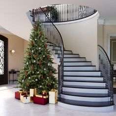 a christmas tree sitting in front of a spiral staircase