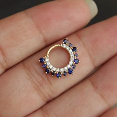 a close up of a person's hand wearing a ring with blue and white stones