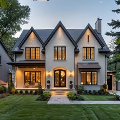 a large white house with lots of windows and lights on it's front porch