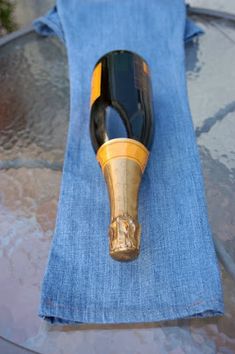 a pair of blue jeans with a black and gold wine bottle in the middle sitting on top of it