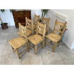 a set of six wooden chairs sitting next to each other on a tile covered floor