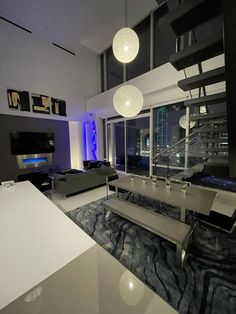 a modern living room with black and white furniture, blue lighting, and large windows