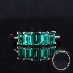 an emerald colored ring sits on a black surface