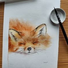 a watercolor painting of a sleeping fox on white paper next to a paintbrush